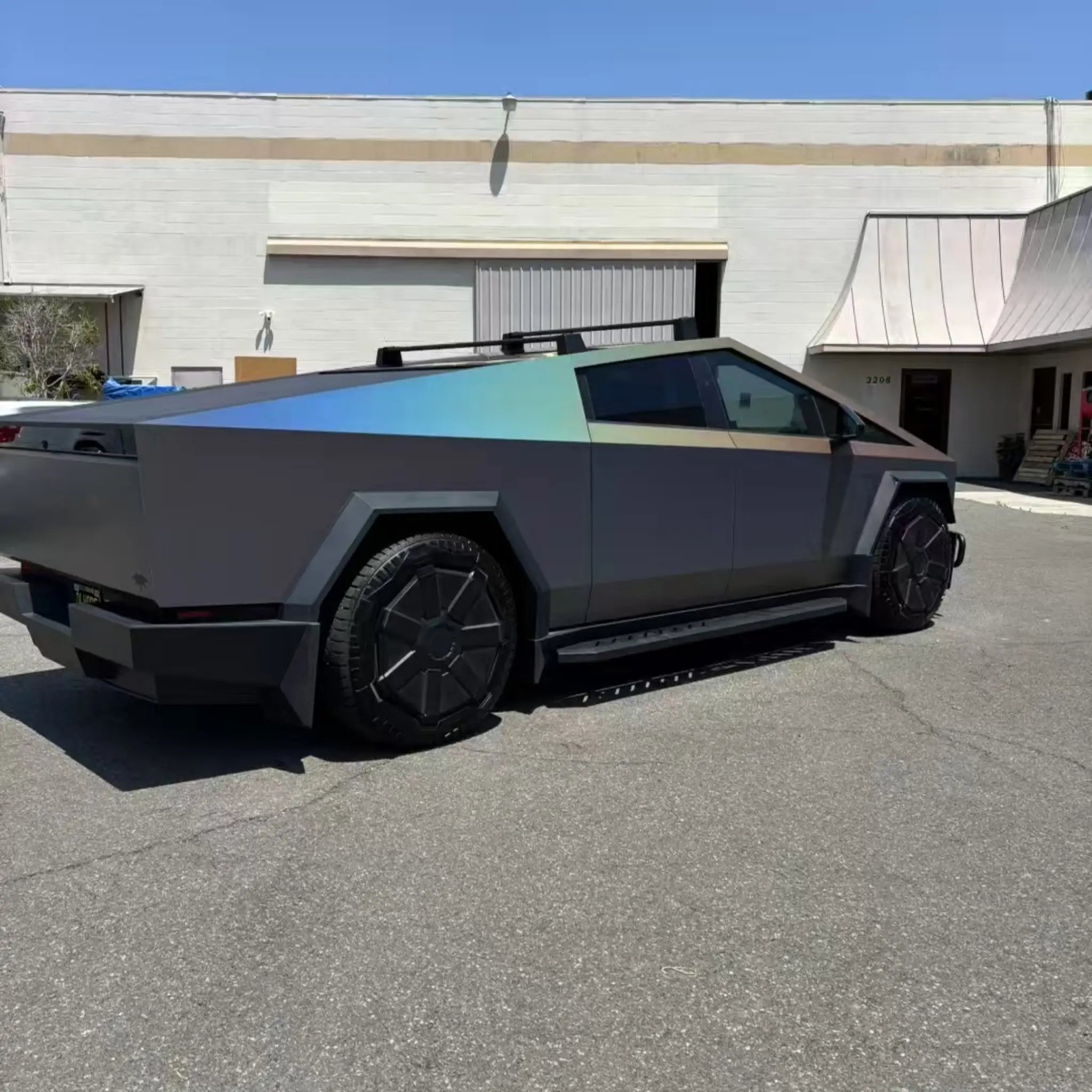 Wide rear-right view of Tesla Cybertruck in Laser Satin Gray vinyl wrap - full vehicle profile in distance - Kaleido