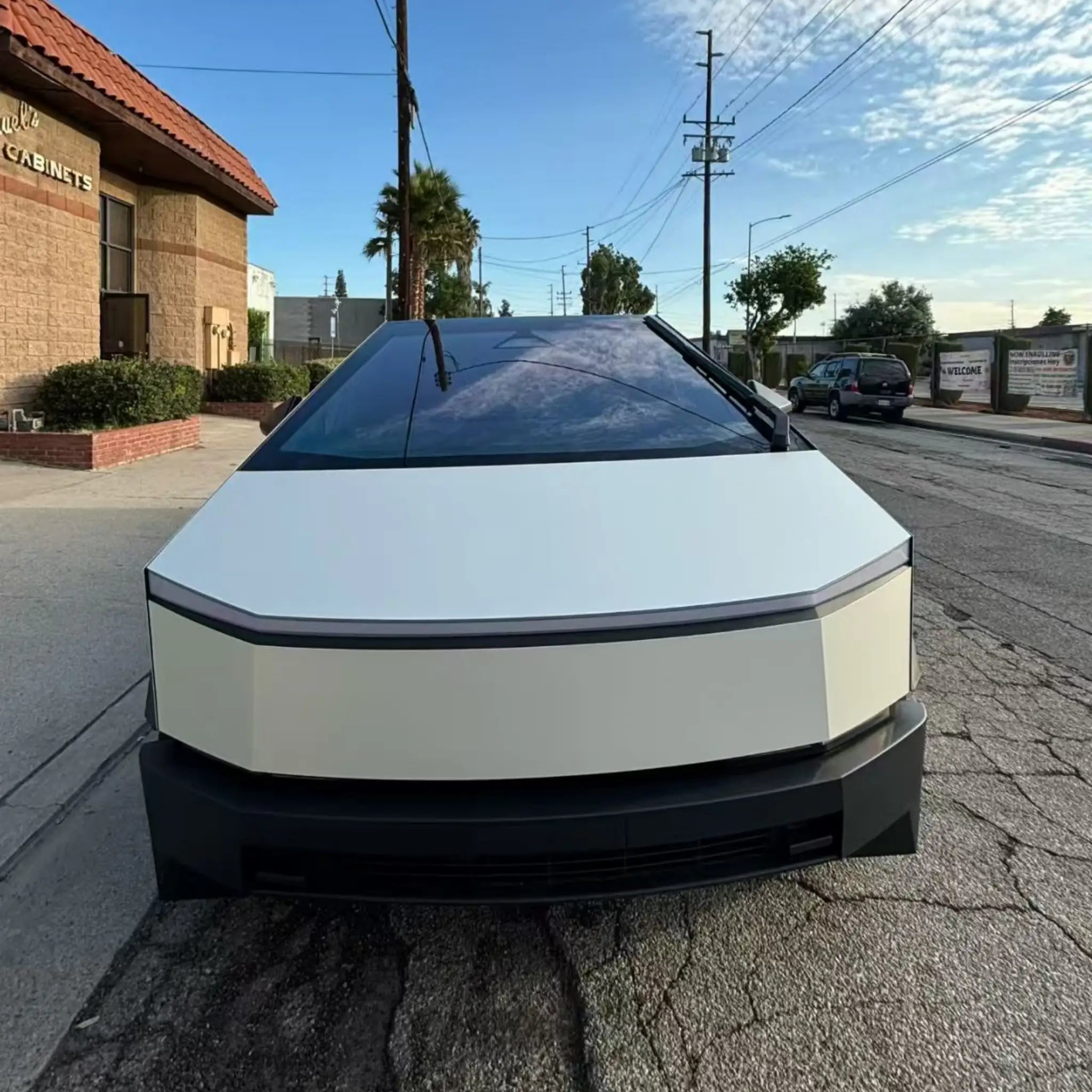Tesla Cybertruck in Matte Lunar White vinyl - front view showcasing angular stainless steel body - Kaleido