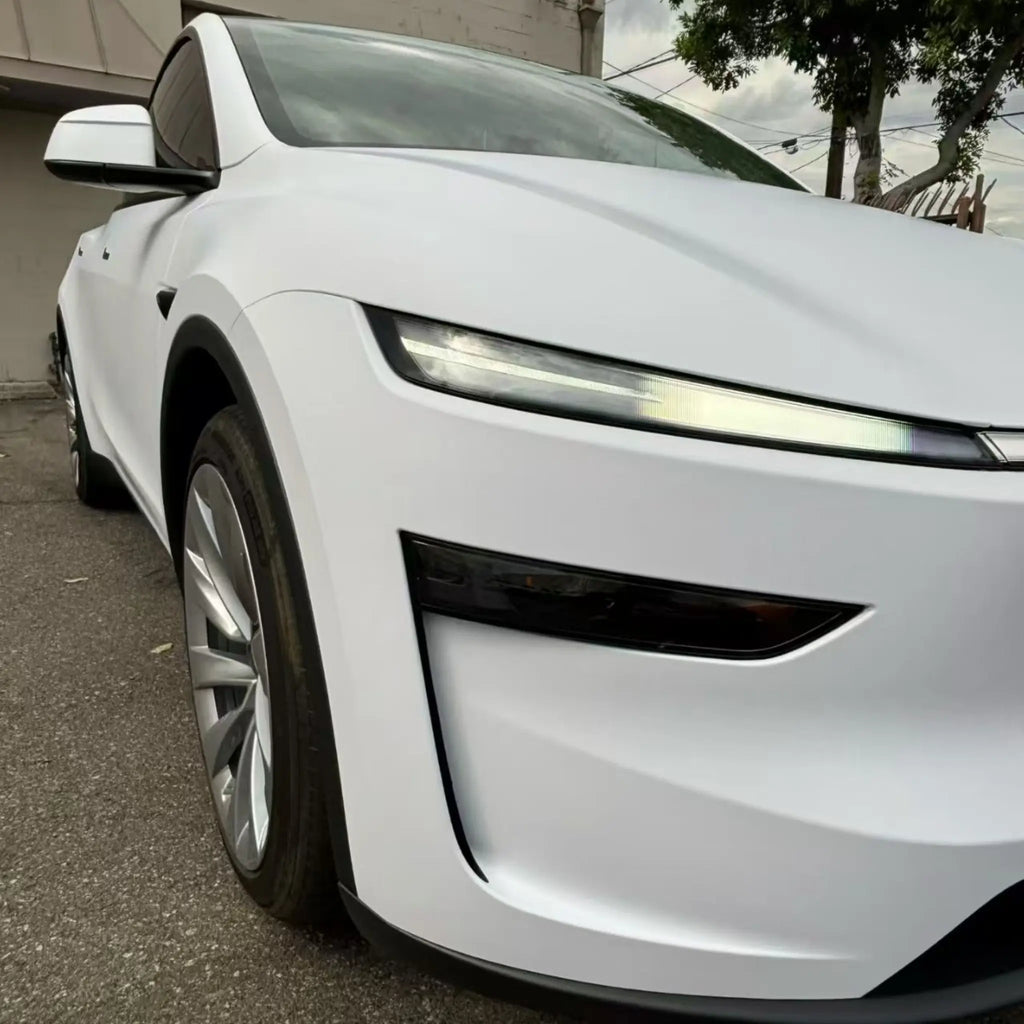 Close-up detail of Matte Lunar White wrap on Tesla Model Y front-right headlight area - Kaleido