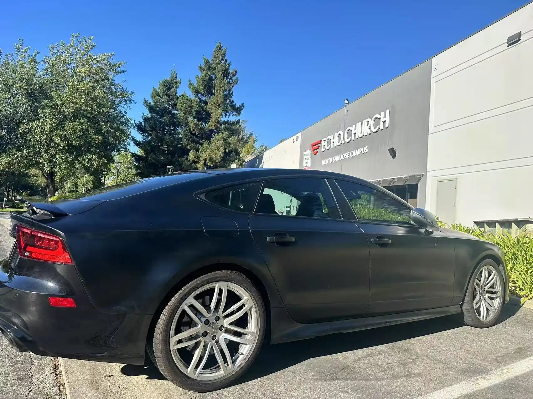 Silky Noir vinyl on Audi RS7 rear-right - showing sleek hatchback design outdoors - Kaleido