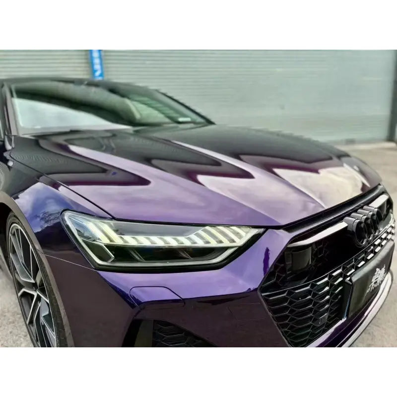 Close-up detail of Midnight Purple Metallic wrap on the front-right grille and headlight of an Audi RS7 - Showcasing the gloss metallic finish - Kaleido