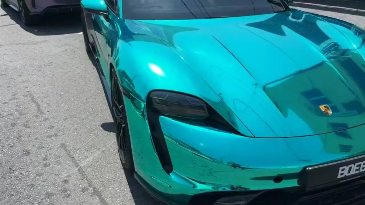 Mirror Chrome Green vinyl wrap on Porsche Taycan front-right - showcasing reflective finish on electric sports sedan - Kaleido