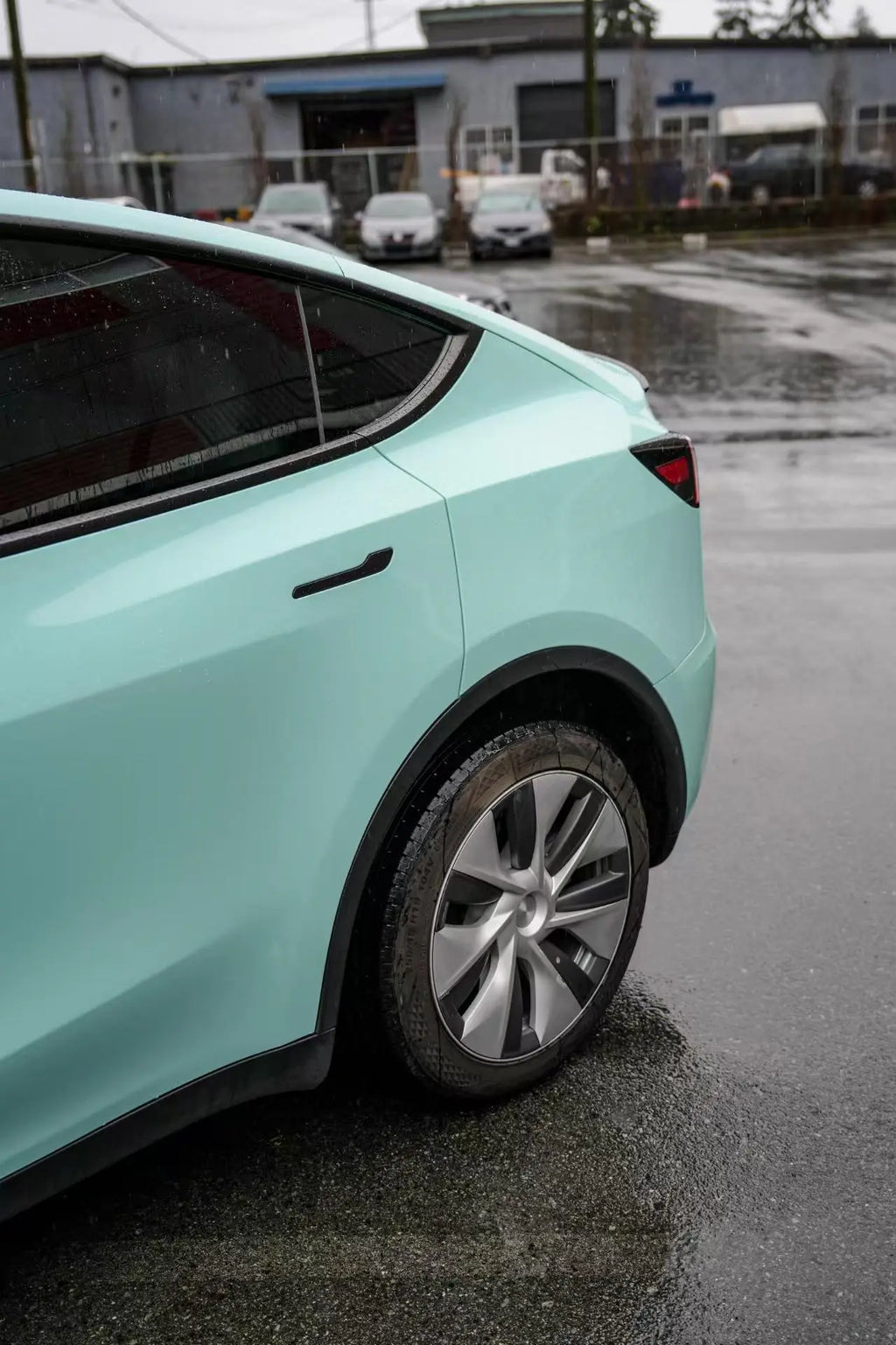 Close-up detail of the rear-left fender on a Sagano Green Tesla Model Y - Kaleido