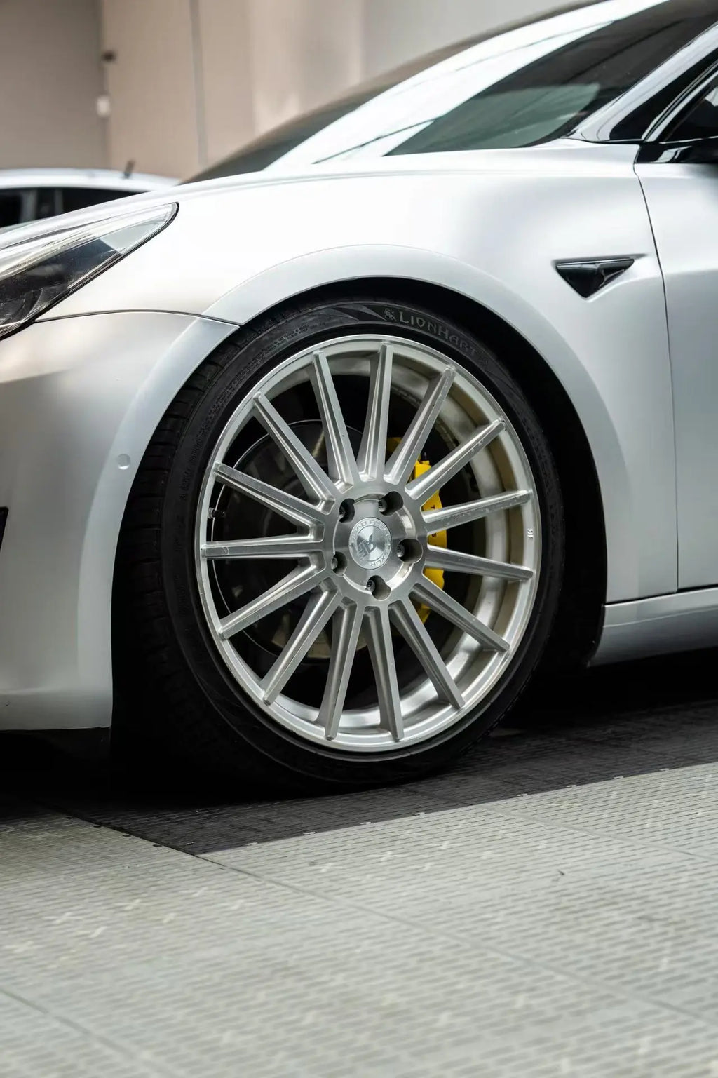 Detailed close-up of the left front corner on a Satin Chrome Alexander Silver Tesla Model 3 - Kaleido