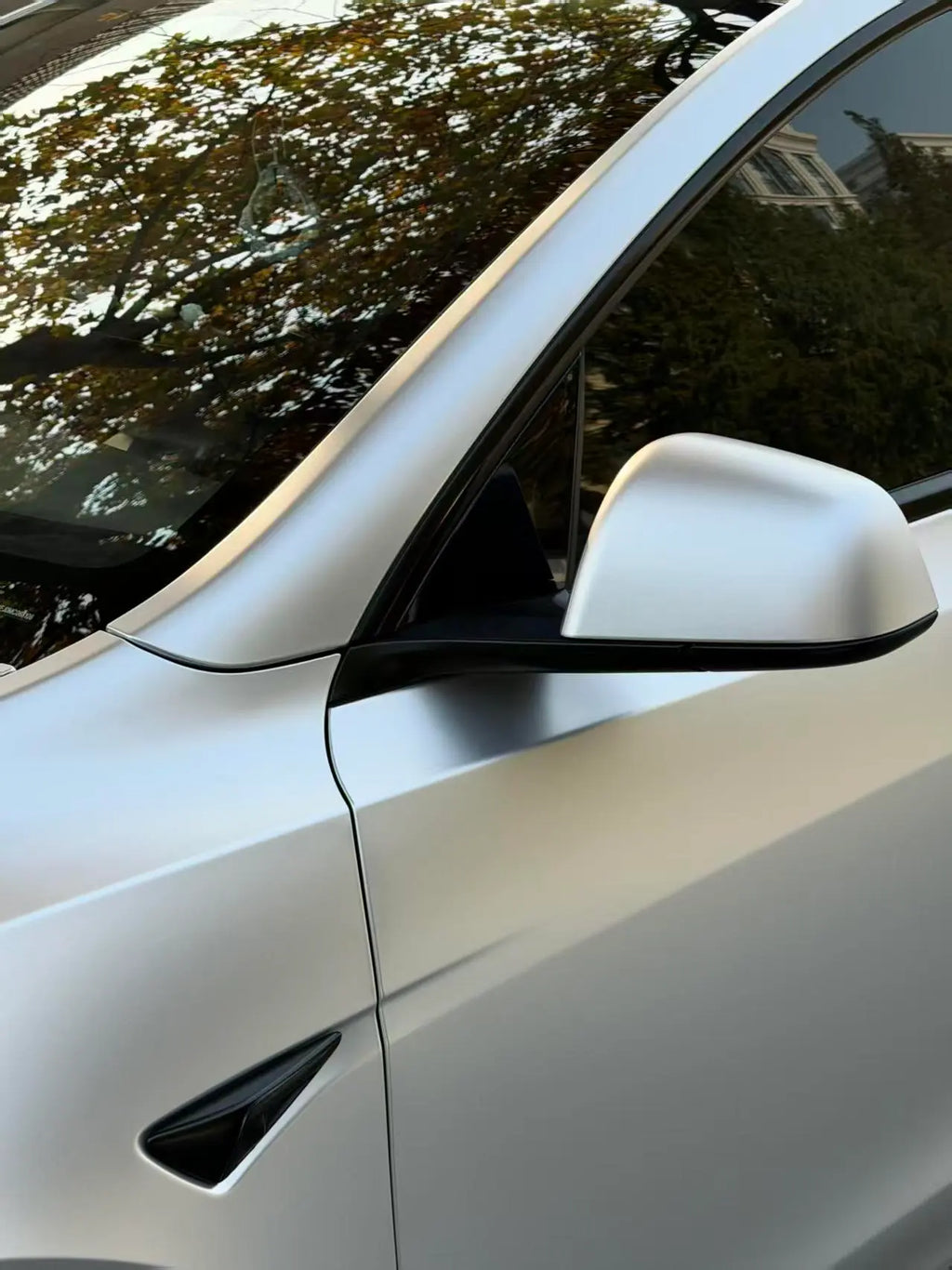 Detailed shot of Satin Chrome Alexander Silver on the left front fender and side mirror of a Tesla Model Y - Kaleido