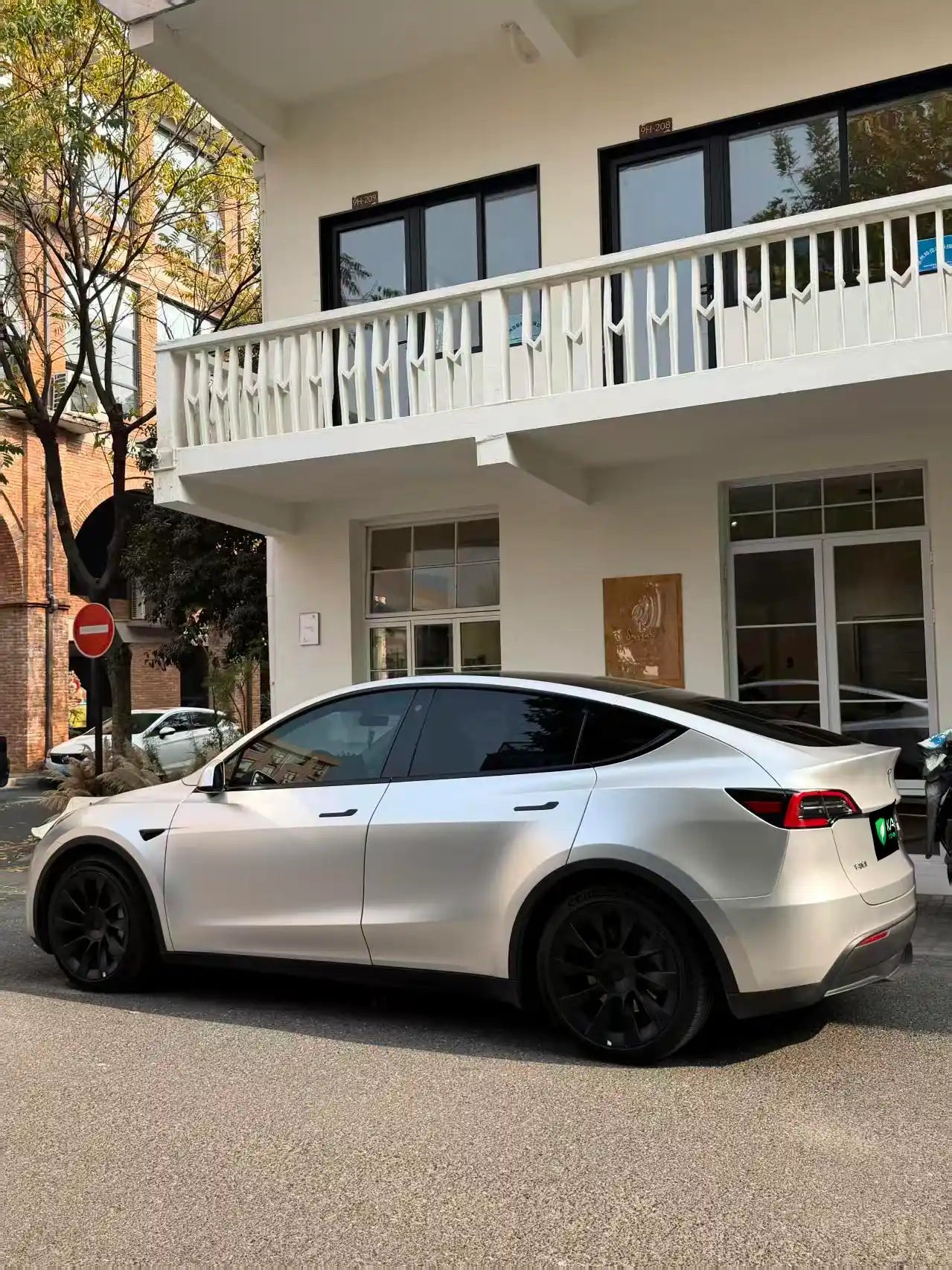 Rear-quarter left view of a Tesla Model Y in Satin Chrome Alexander Silver vinyl - highlighting rear fender - Kaleido