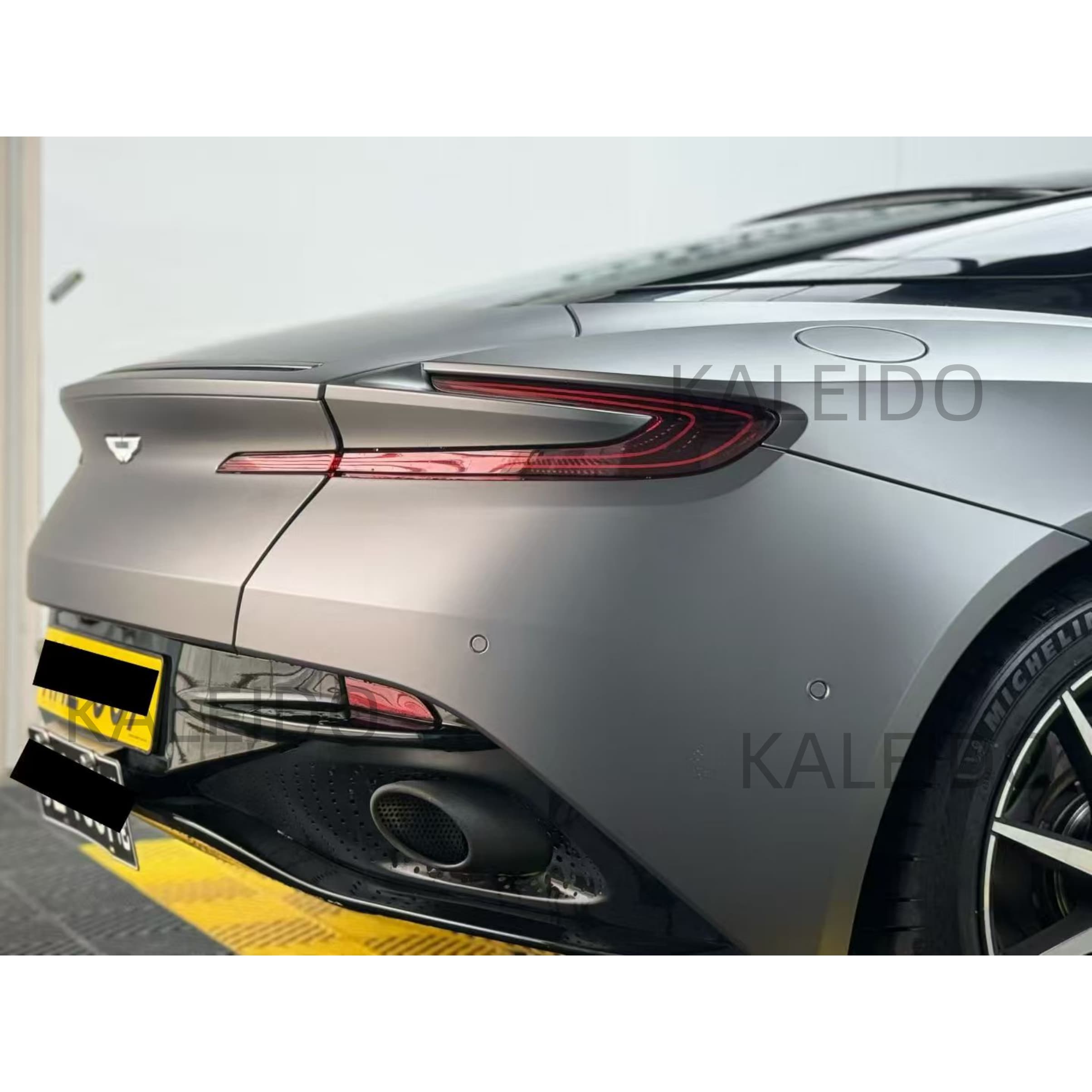 Satin chrome wrap on the muscular rear quarter panel of an Aston Martin DB11 - Kaleido