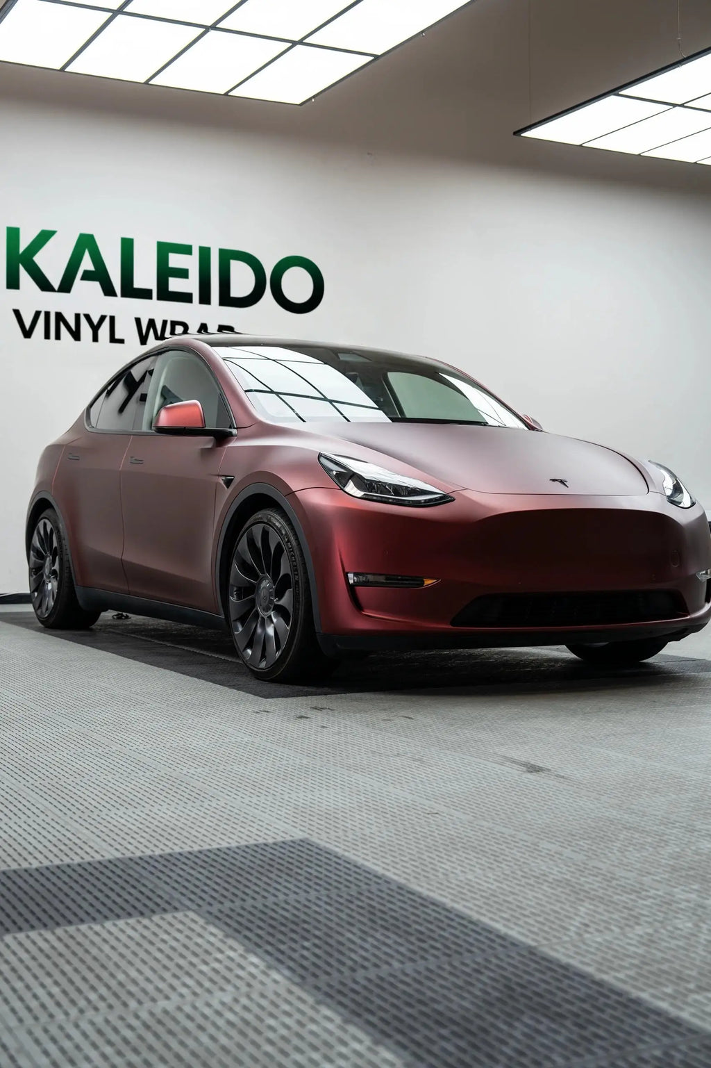 Wide front-right view of Tesla Model Y with Satin Chrome Silk Red matte metallic finish - Kaleido