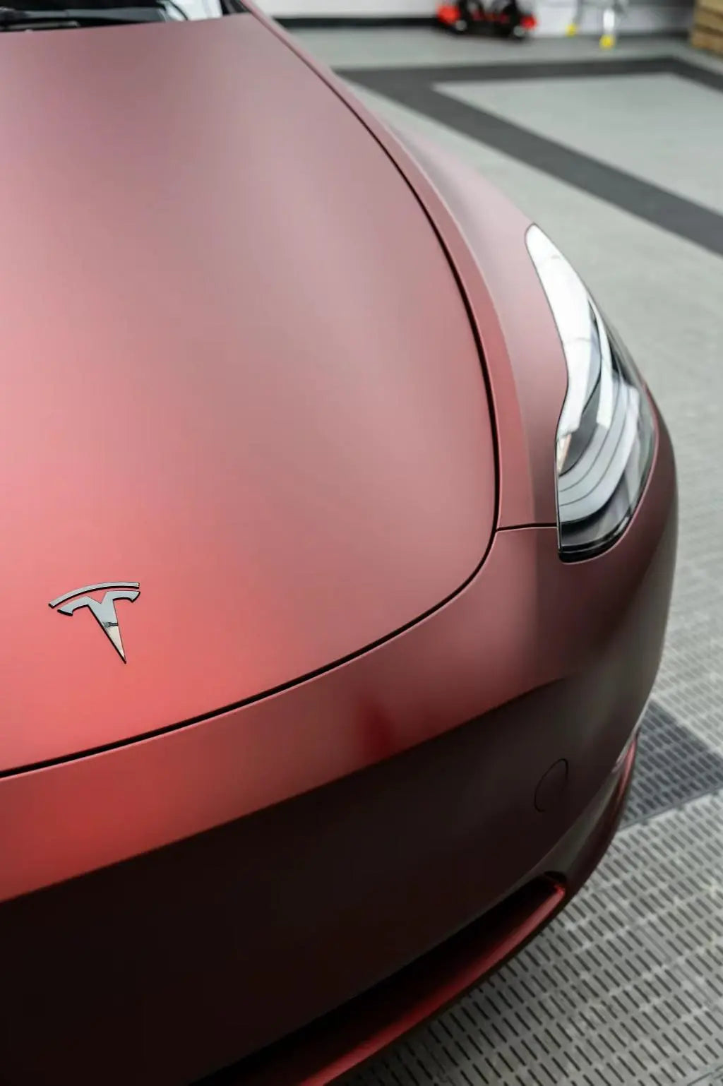 Close-up of Satin Chrome Silk Red film on Tesla Model Y hood - showcasing silken matte texture - Kaleido