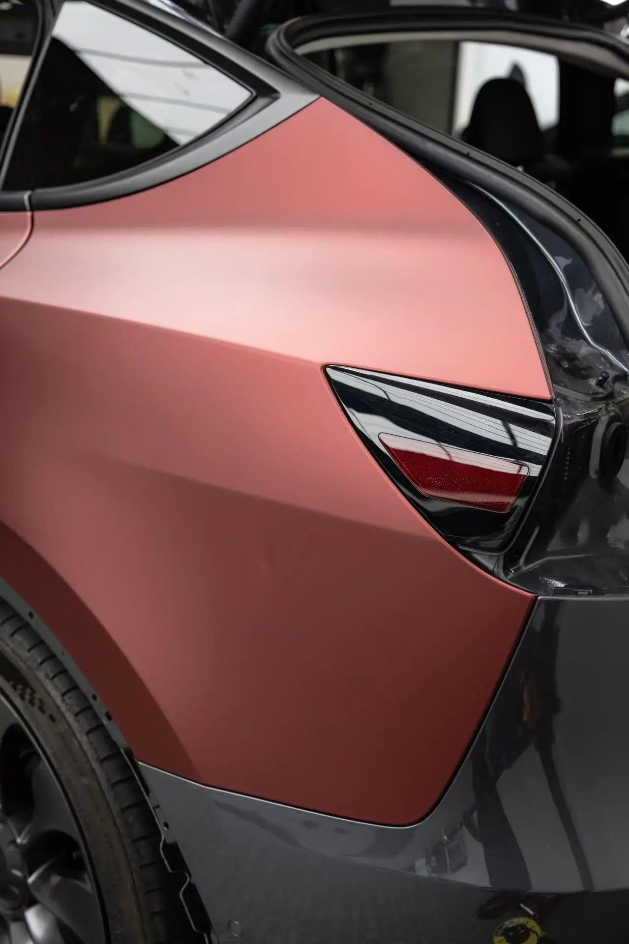 Detailed view of Satin Chrome Silk Red vinyl on Tesla Model Y left rear fender - Kaleido