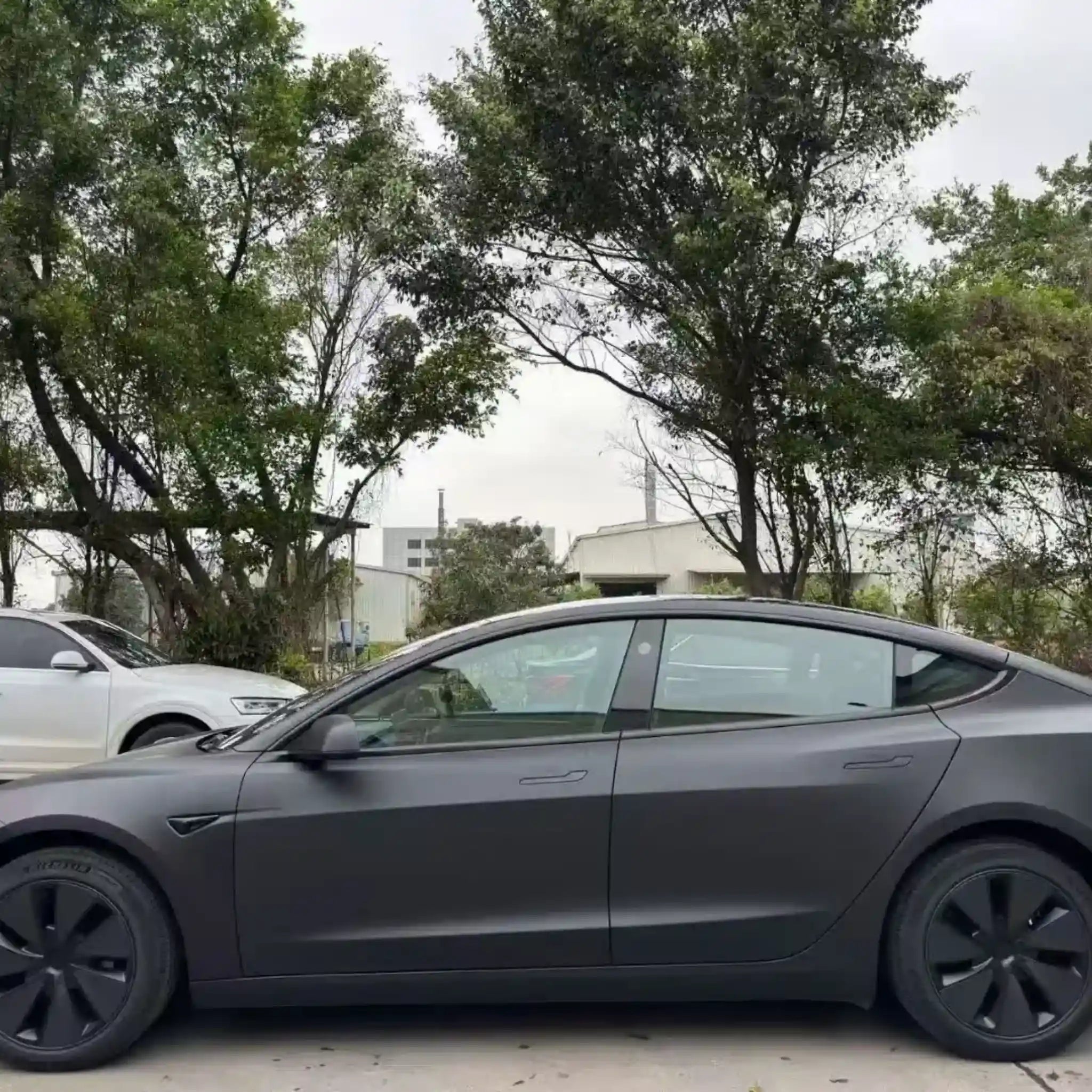 Tesla Model 3 in Stealth Matte Black vinyl wrap - left side profile showing non-reflective matte finish - Kaleido