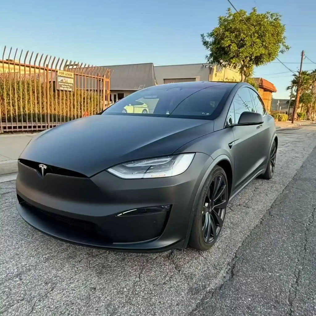 Outdoor close-up of Stealth Matte Black wrapped Tesla Model X - left front corner with natural light - Kaleido